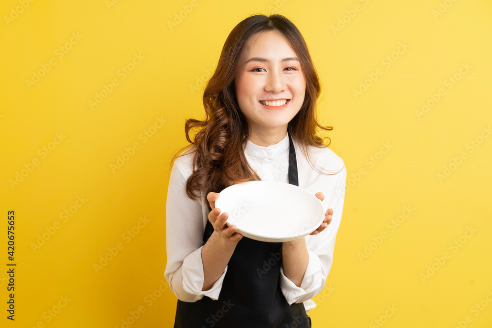Beautiful housewife holding plate isolated on golden background Beautiful housewife holding plate isolated on golden background