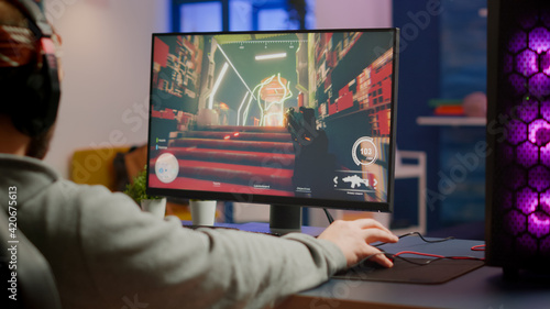 Fotografie Gamer man with professional headphones relaxing in gaming room playing shooter video game on powerful computer