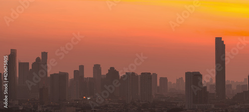 Air pollution. Smog and fine dust of pm2.5 covered city in the morning with orange sunrise sky. Cityscape with polluted air. Dirty environment. Urban toxic dust. Unhealthy air. Urban unhealthy living. © Artinun