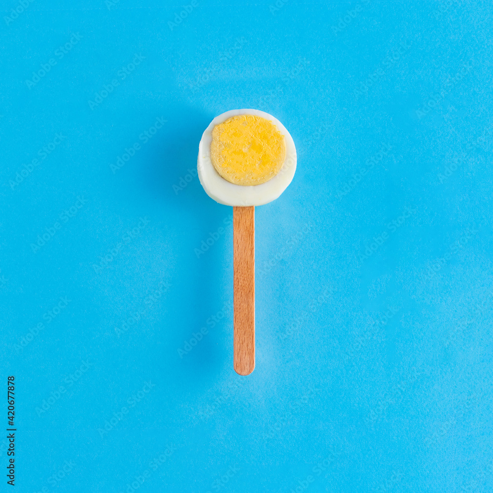 A slice of Easter egg on a stick like ice cream on a blue background. Minimal creative concept of Easter or food. Flat lay A slice of Easter egg on a stick like ice cream on a blue background. Minimal creative concept of Easter or food. Flat lay