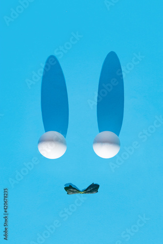 Easter 2021 creative composition with white eggs and green leaves on a light blue background. Minimal spring holiday concept. Flat lay.