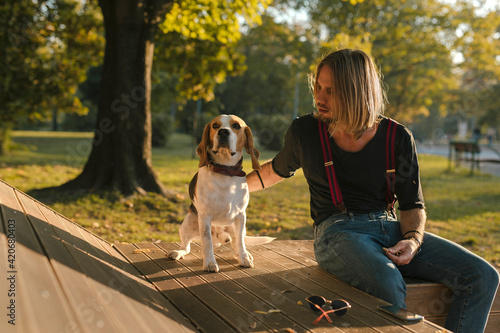 Man Sitting On A Bench With His Beagle Dog photo