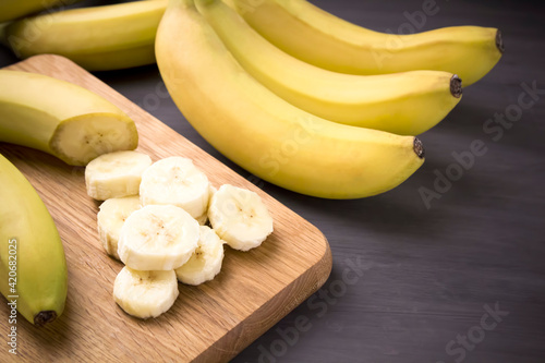 A bunch of bananas and a sliced banana  on a table.
