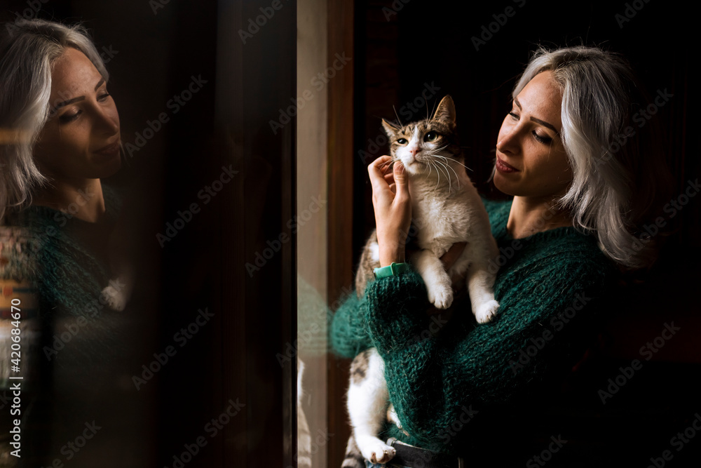Woman in front of the window with her cute cat, looking outdoor. Woman in front of the window with her cute cat, looking outdoor.