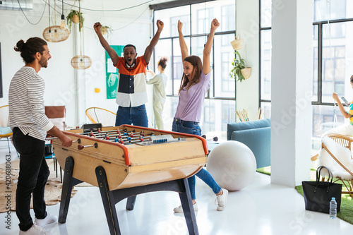 Diverse colleagues playing foosball in workplace photo