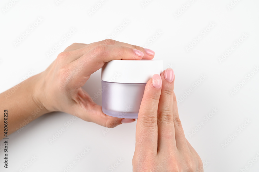 Female hands hold a jar of cream, on an isolated background Female hands hold a jar of cream, on an isolated background