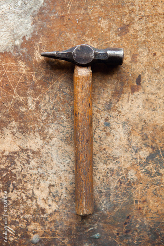 A hammer seen on an old wooden workbench