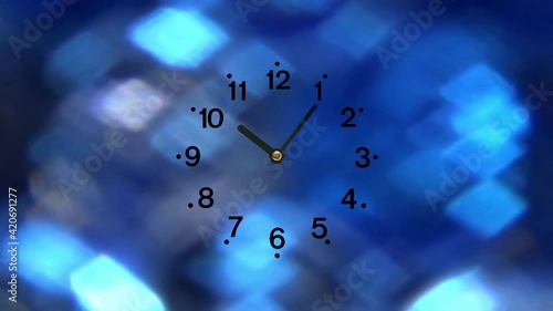 12時間を早回しで秒針の無い針が逆回転するアナログの時計。煌めく青い光の背景。文字板が透明な時計。