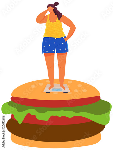 Overweight young woman on scales is standing on huge burger. Diet and proper nutrition concept