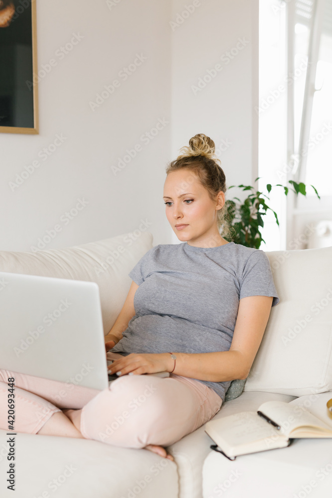 Woman working from home using laptop while sitting on the sofa Woman working from home using laptop while sitting on the sofa