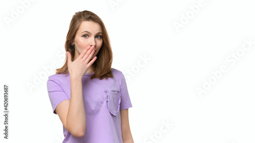 Obraz na plátne Young woman covering mouth with hand, looking serious, promises to keep secret