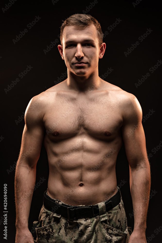 Fototapeta premium Studio shot of muscular topless military man on black background
