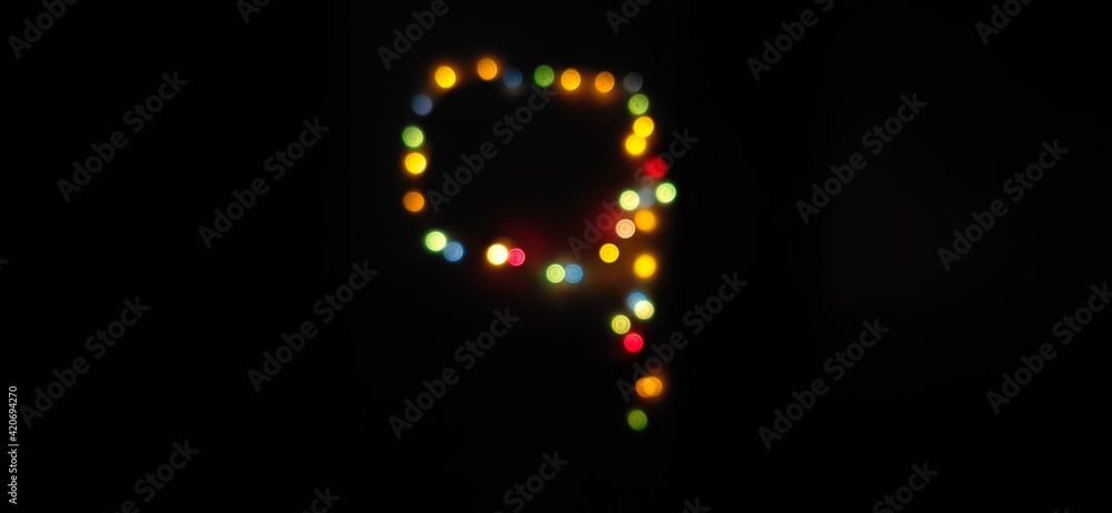 Closeup of Number nine, (9) made with multicolored blurred bokeh Christmas lights in a isolated black background with copy space