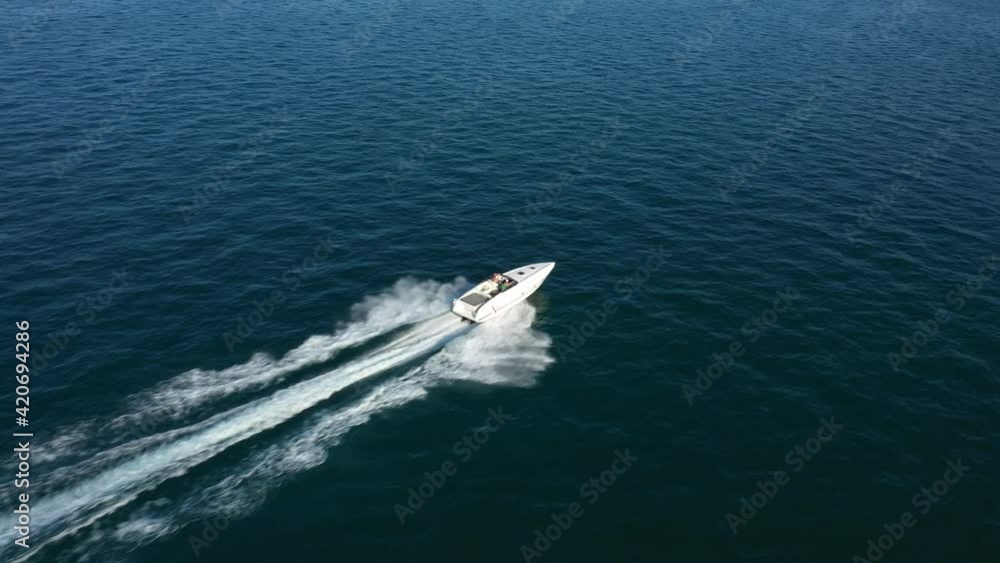 Drone shooting 4k video. Flying over the boat top view. A speedboat of white color in the rays of the sun moves quickly on blue water, top view. Aerial video. Drone shooting 4k video. Flying over the boat top view. A speedboat of white color in the rays of the sun moves quickly on blue water, top view. Aerial video.