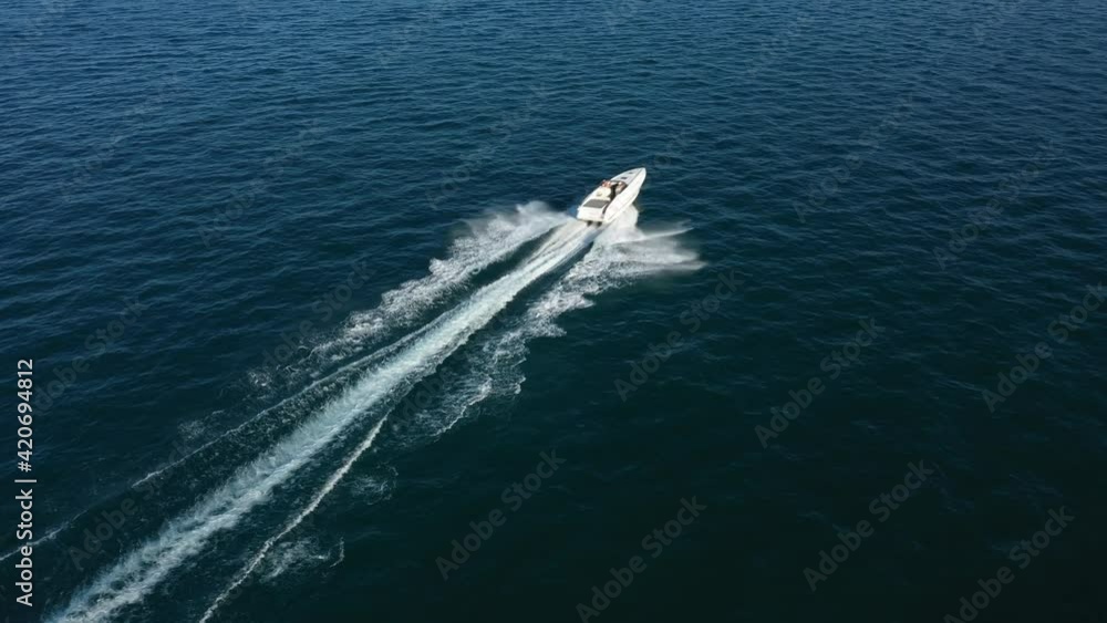 Flying over the boat top view. A speedboat of white color in the rays of the sun moves quickly on blue water, top view. Drone shooting 4k video. Aerial video. Flying over the boat top view. A speedboat of white color in the rays of the sun moves quickly on blue water, top view. Drone shooting 4k video. Aerial video.