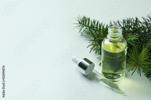 Bottle of pine oil and twig on white background