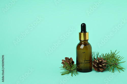 Pine oil, cones and twigs on mint background