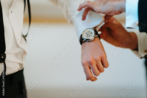 Men helping groom putting on shirt photo