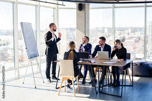 The boss stands near the board with graphs, demonstrates statistics, various personnel attending the training, introduces the new products of the company, reports on the results of work for partners.