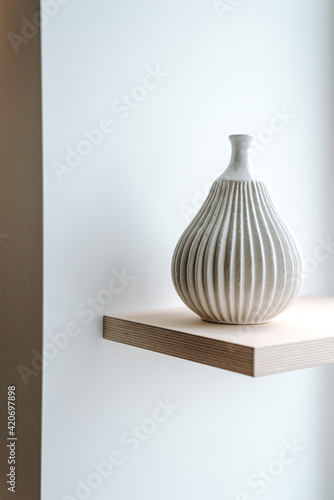 Modern white vase on a wooden shelf photo