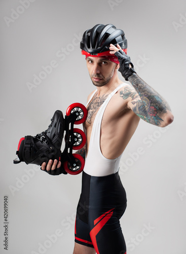 фотографія a man in sports clothes and a helmet with roller skates in his hands on a white