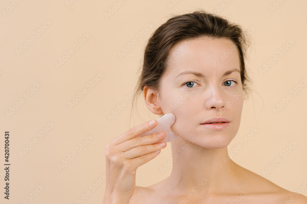 Woman massaging face with gua sha scraper Woman massaging face with gua sha scraper