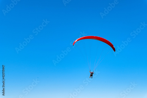 Panoramic photo of two people paraglider in blue sky