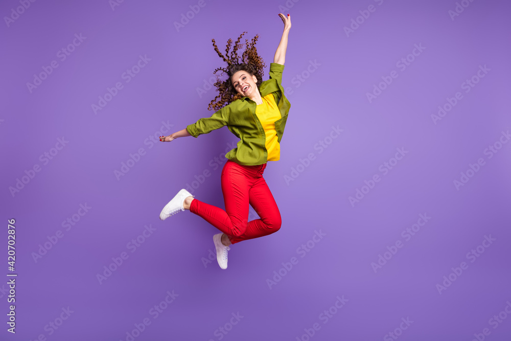 Full size photo of young happy excited positive good mood girl with wavy hair jumping isolated on violet color background