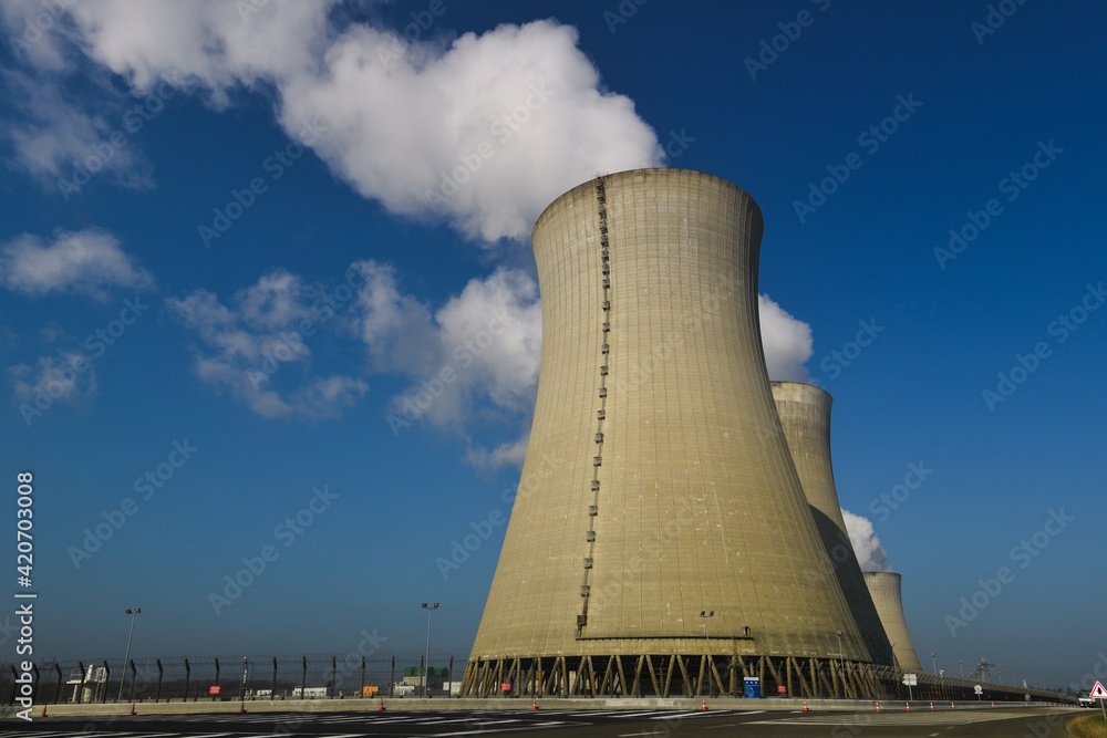 Tours de refroidissement d'une centrale nucléaire d'où sort de la vapeur d'eau en fumée blanche sur fond de ciel bleu
