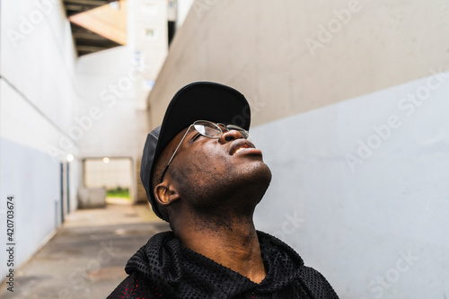 Young urban man looking up to the sky in narrow alley in city photo