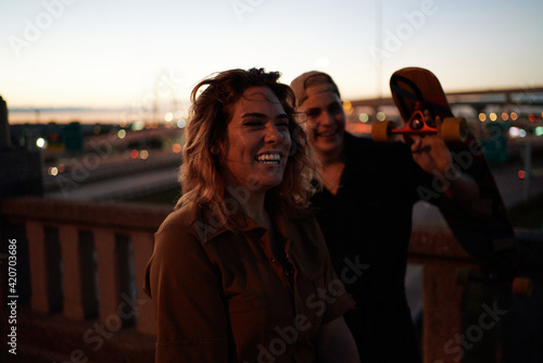 Couple friends with stylish outfits laughing together over the city lights. photo