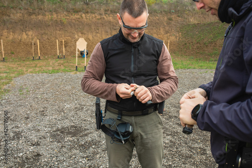 Two shooters are putting bullets into gun cartridges on a practical shooting training photo