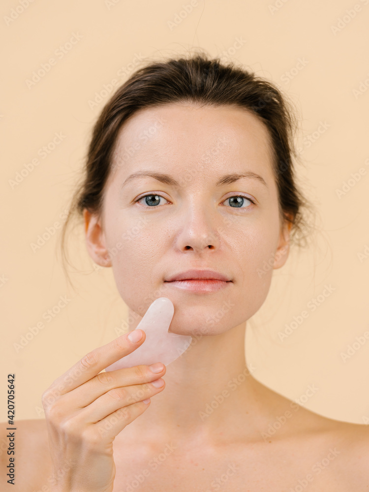 Woman massaging face with gua sha scraper Woman massaging face with gua sha scraper