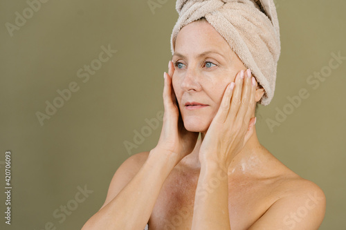 Gentle woman applying facial cream after shower