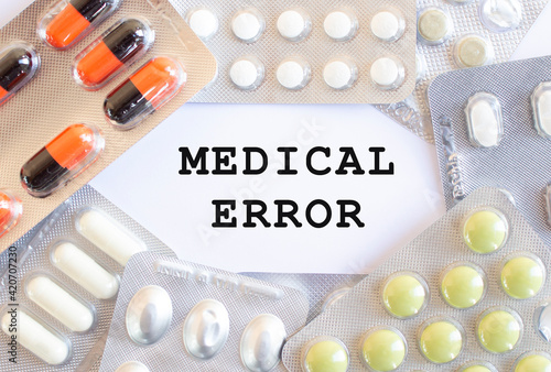 Text MEDICAL ERROR on a white background. There are different medicines around.