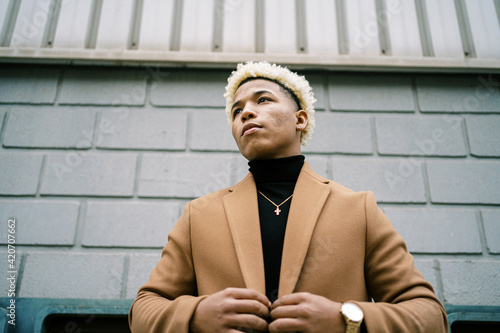 Stylish black man in trendy coat standing on street photo