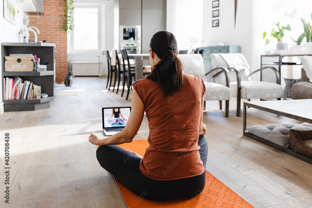 © Michela Ravasio/Stocksy - Brunette woman taking an online yoga class at home © Michela Ravasio/Stocksy - Brunette woman taking an online yoga class at home
