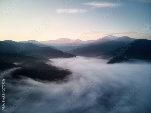 Aerial view  sea of fog and clouds illuminated by the rising sun  snow on the tops of the mountains. Russia