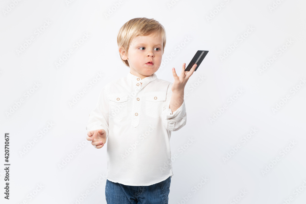 Kid money, child card. Cute boy in a white shirt on a white background holds a bank card in his hand Kid money, child card. Cute boy in a white shirt on a white background holds a bank card in his hand