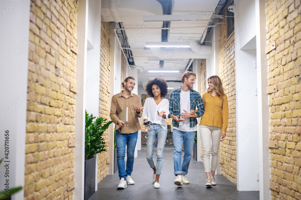 Obraz premium Group of smiling young people walking in the corridor
