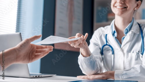 Smiling doctor giving a prescription to a patient