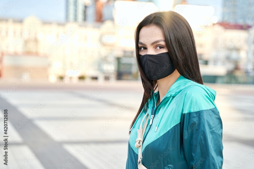 Young lady wearing protective face mask posing at camera outdoor
