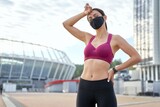 Athletic lady in black safety mask tired of jogging