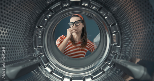 Woman looking into her smelly washing machine photo