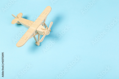 Model of a wooden toy plane, airliner, on a blue background. the concept of travel and transport and children's fantasies