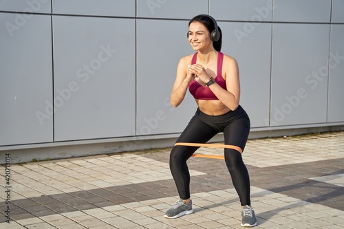 Happy beautiful female listening to music while squatting