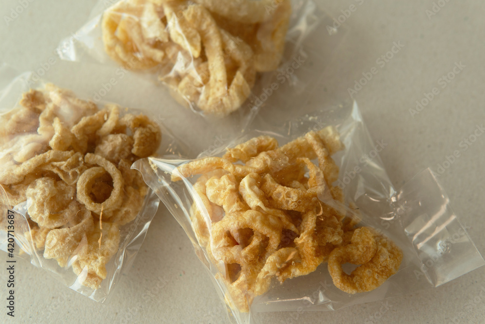 Pork crackle in package plastic bag on organic paper background with natural light Pork crackle in package plastic bag on organic paper background with natural light