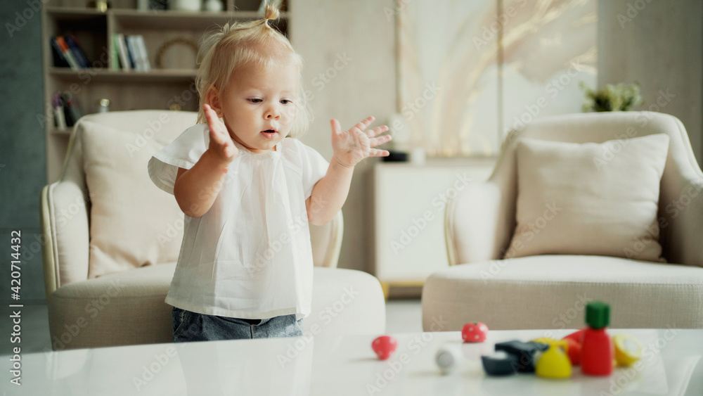 Children learn at home. The child plays with children's wooden colored educational mind toys. Portrait of a cute little blonde girl. A cheerful mood. A happy family spends time at home. Children learn at home. The child plays with children's wooden colored educational mind toys. Portrait of a cute little blonde girl. A cheerful mood. A happy family spends time at home.