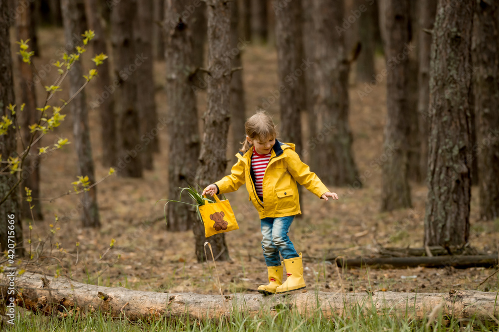 Adorable little girl hiking in forest. Kid in yellow coat and boots in beautiful nature. Sustainable renovation. Adorable little girl hiking in forest. Kid in yellow coat and boots in beautiful nature. Sustainable renovation.