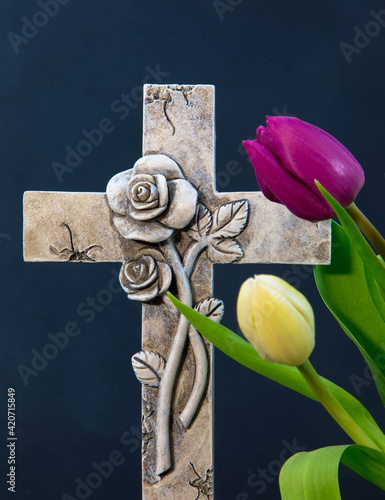 Close up of religious cross and tulip flowers on dark Background for obituary notice. Funeral and mournig concept.  photo